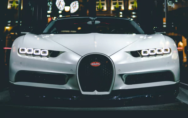 Front view of a white Bugatti Chiron at night, headlights and grille glowing against city lights — 4K Ultra HD PC desktop wallpaper and background.