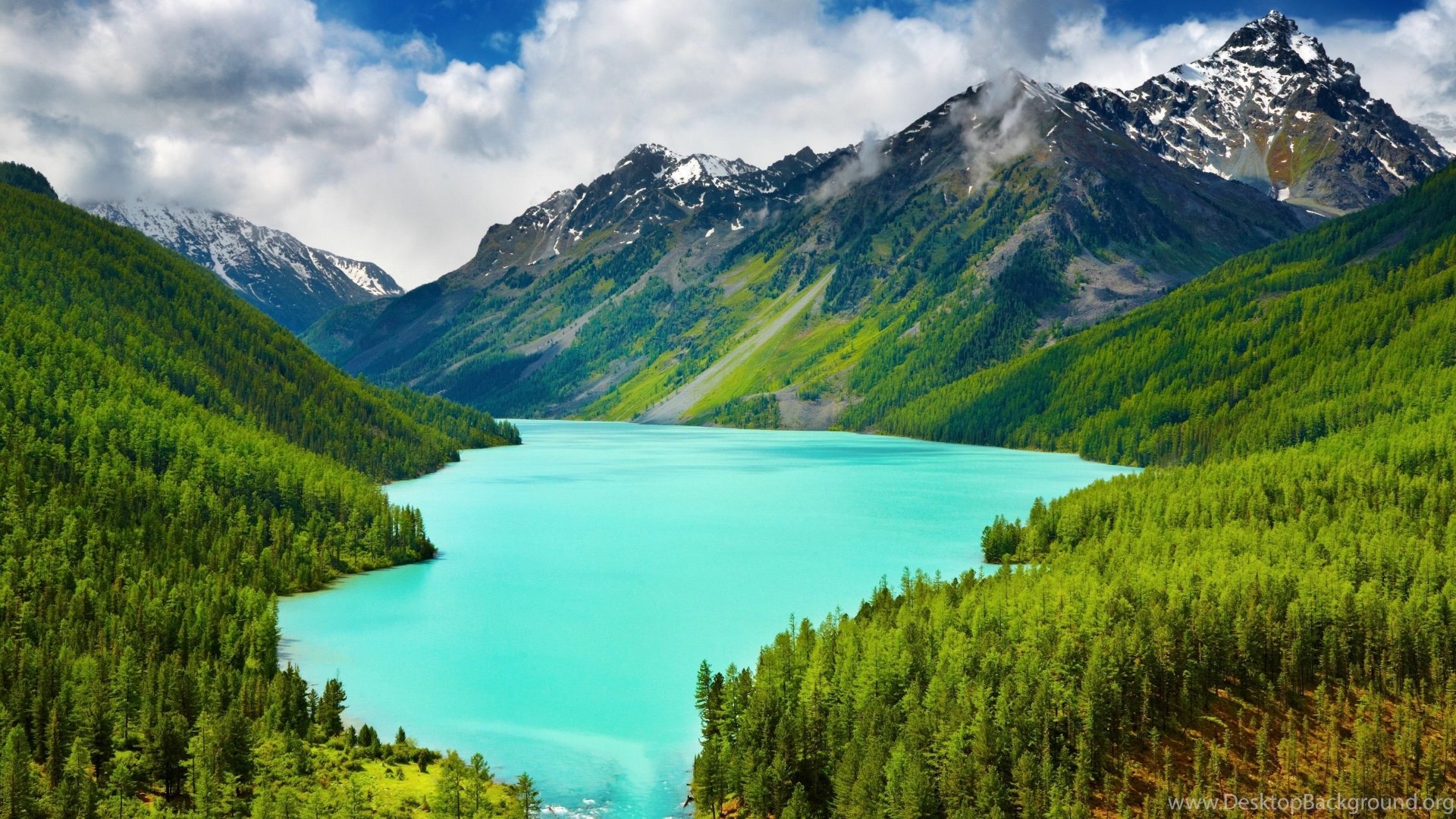 A stunning 4K Ultra HD desktop wallpaper featuring turquoise lake surrounded by lush green forests, towering mountains, and a sky filled with clouds.