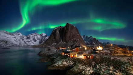 HD desktop wallpaper showcasing the vibrant aurora borealis over snowy mountains and a coastal village in Lofoten, Earth, captured through stunning photography.