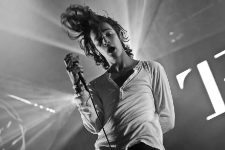 HD wallpaper of The 1975 in concert with a dynamic black and white image of the lead singer performing.